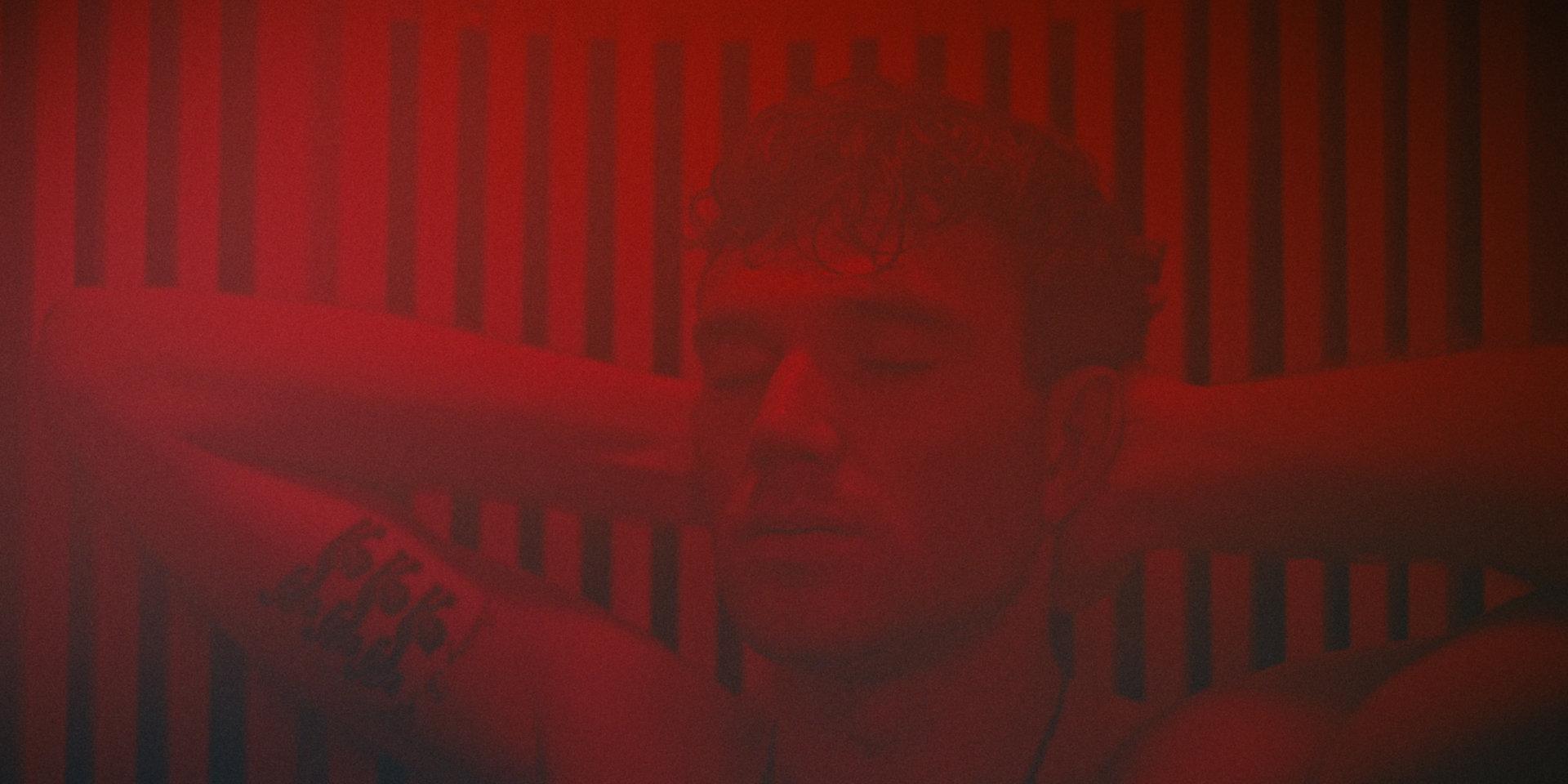 Jack Draper resting with his eyes closed and arms behind his head in front of a red light panel.