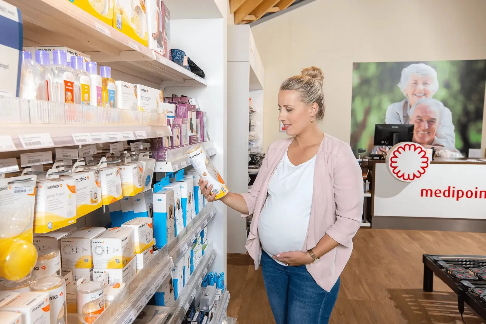 Zwangere vrouw loopt in een Medipoint winkel en kijkt met interesse naar alle producten voor de zwangerschaps- en kraamperiode.