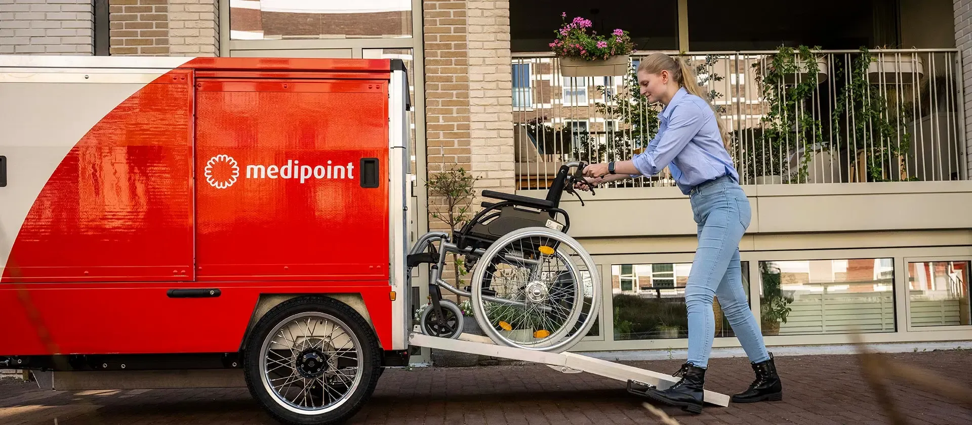 Medipoint medewerker duwt rolstoel in een voertuig