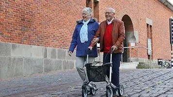 Man loopt met een rollator, vrouw loopt ernaast
