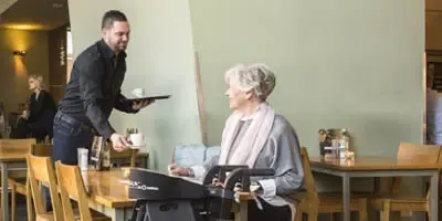 Mevrouw met een Travixx rollator in een restaurant