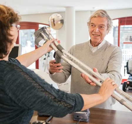 Een man en vrouw staan in een kamer met een kruk, klaar om een hulpmiddel te testen met een expert.