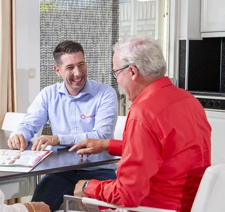 Twee mannen aan een tafel, bespreken advies over hulpmiddelen voor zelfstandig wonen en mobiliteit