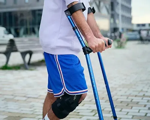 Man op krukken in de stad met een brace om de knie