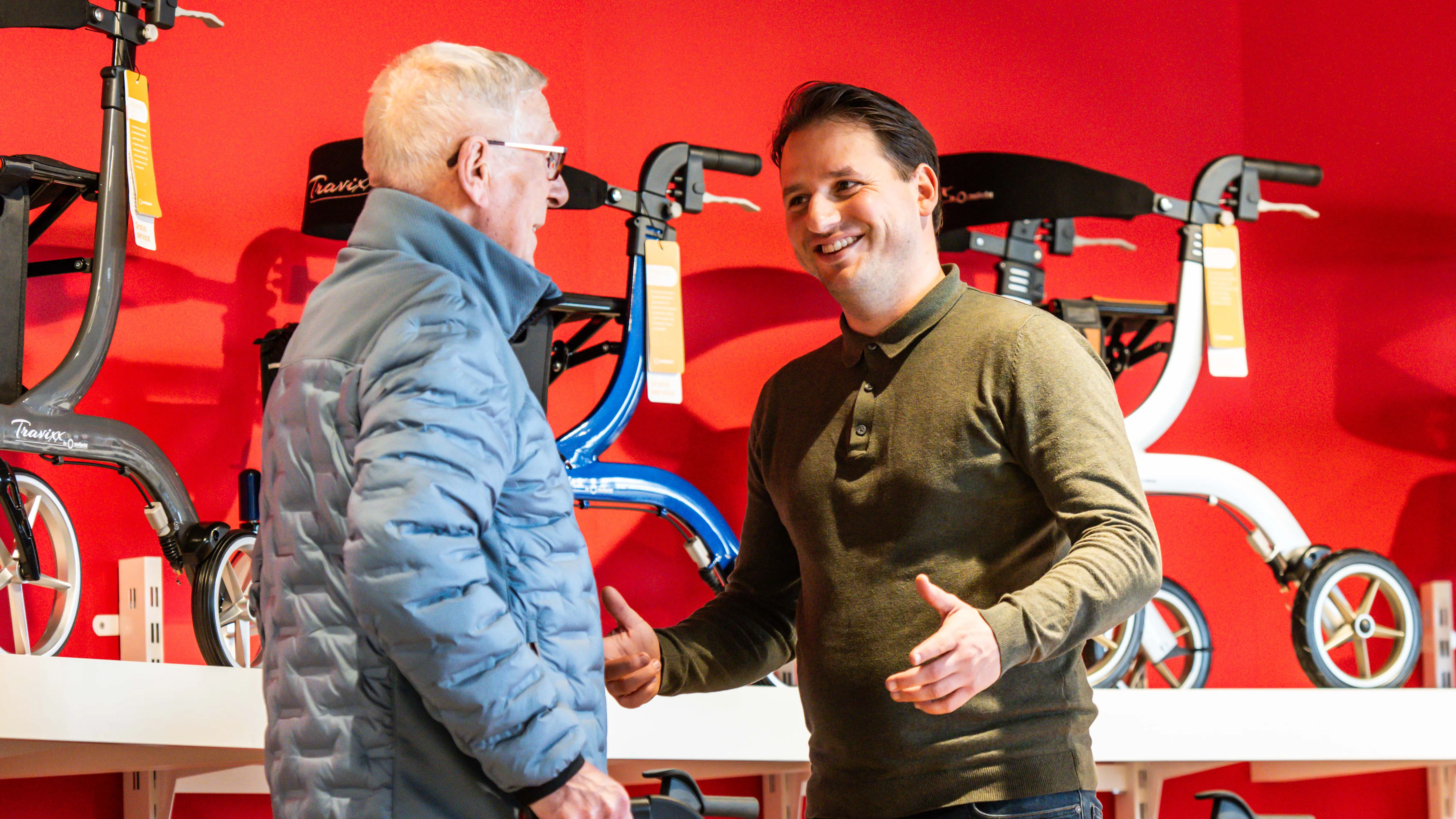 Een winkelmedewerker geeft advies aan een klant. Ze staan bij de rollators