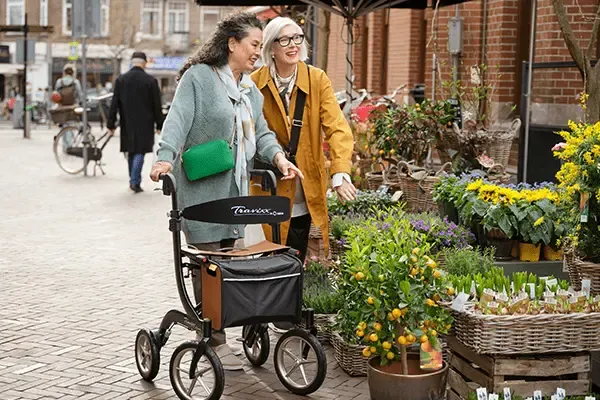 2 vrouwen waarvan 1 met een rollator bij een bloemenwinkel