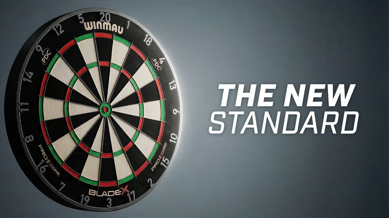 Winmau Blade X Dartboard on a gray wall with text "The New Standard" beside it.