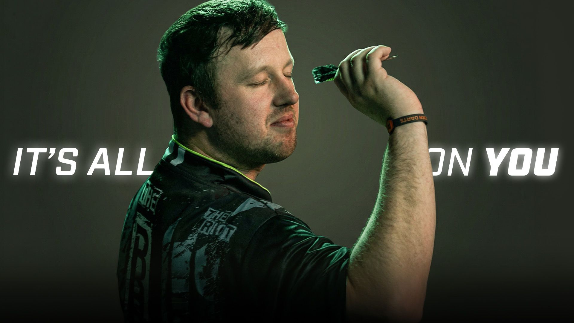 Callan Rydz holding a dart confidently, eyes closed against a dark background, with the text "It's all on you" beside him.