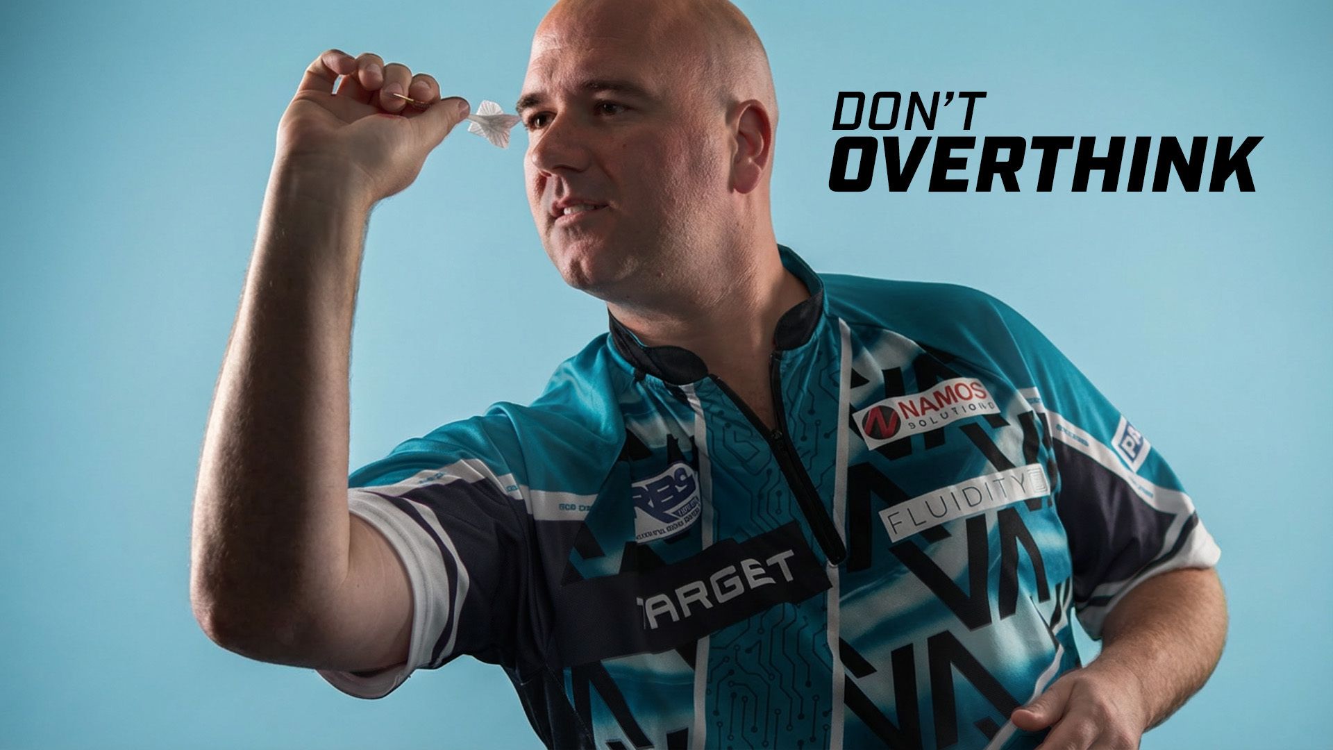 Rob Cross aims a dart, wearing a blue and black shirt with sponsors' logos. The background is blue with the text "DON'T OVERTHINK."