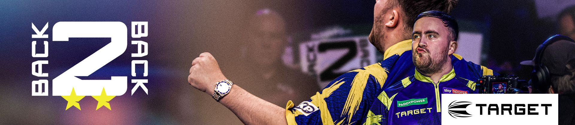 Luke Littler in a blue and yellow dart shirt celebrating with clenched fists. Text reads "Back 2 Back" with stars. Target logo visible.