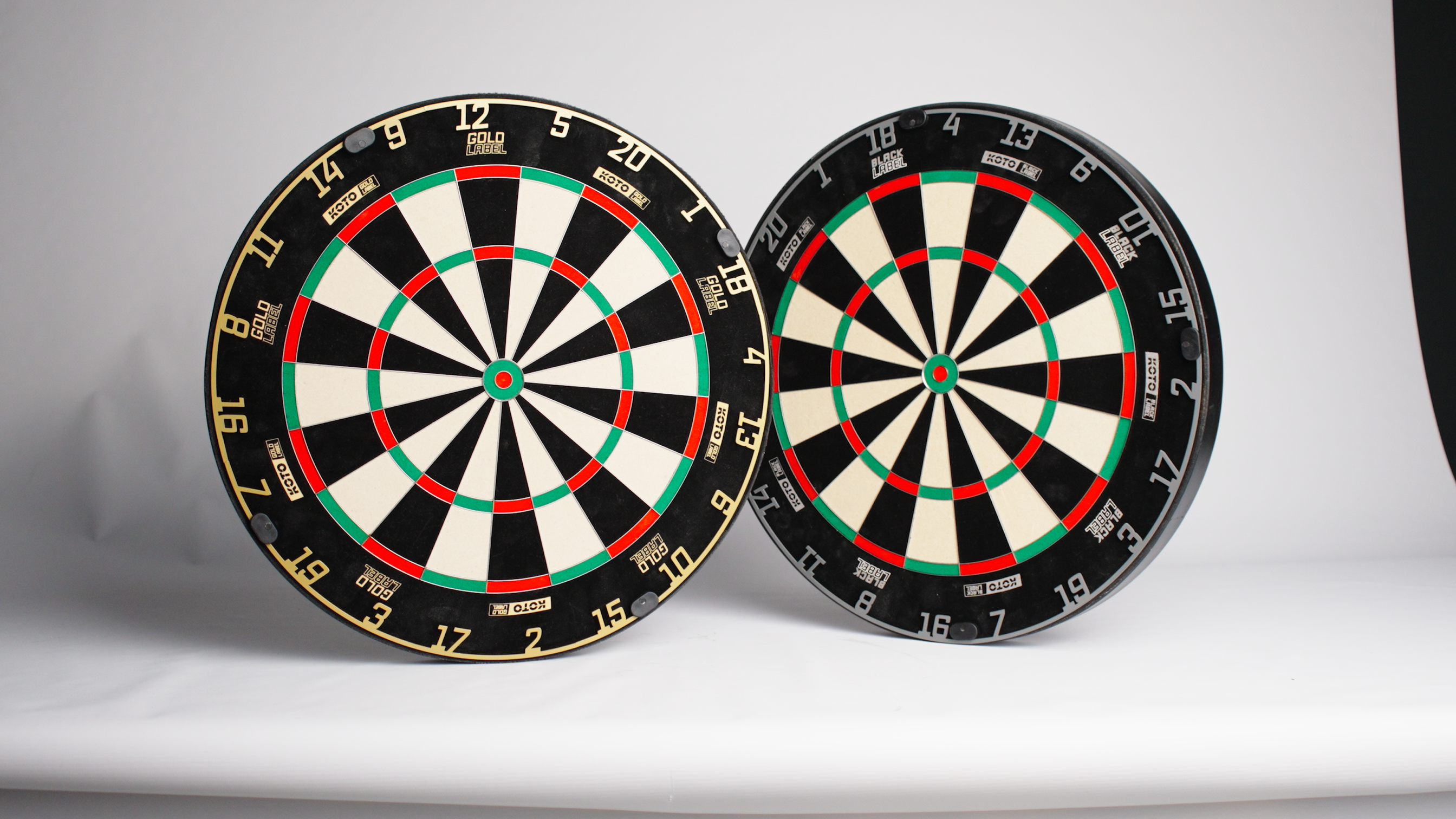 Two dartboards placed side by side, featuring black, white, green, and red segments with numbered sections around the edges.