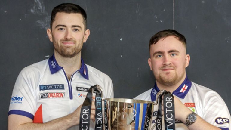 Two men in white shirts holding a trophy adorned with "BetVictor" ribbons, smiling at the camera.