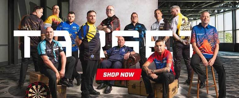 A group of men in colorful dart jerseys posed in a room with large windows. A dartboard is on the floor, and a "Shop Now" button is prominent.