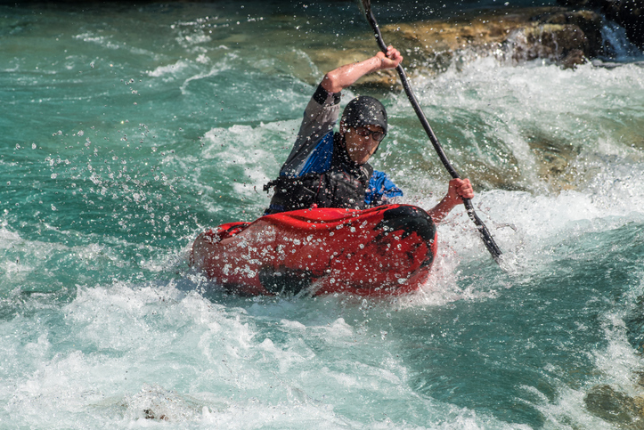 Woman in a coat and scarf standing indoors near a sign that reads 