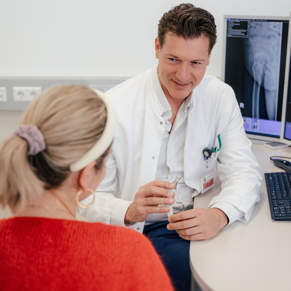 Eine lächelnde Ärztin oder Krankenschwester mit einem Stethoskop berät einen Patienten.