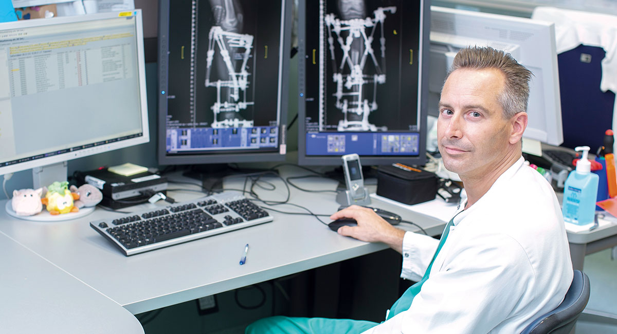 Arzt sitzt am Computer mit Rötngenbild