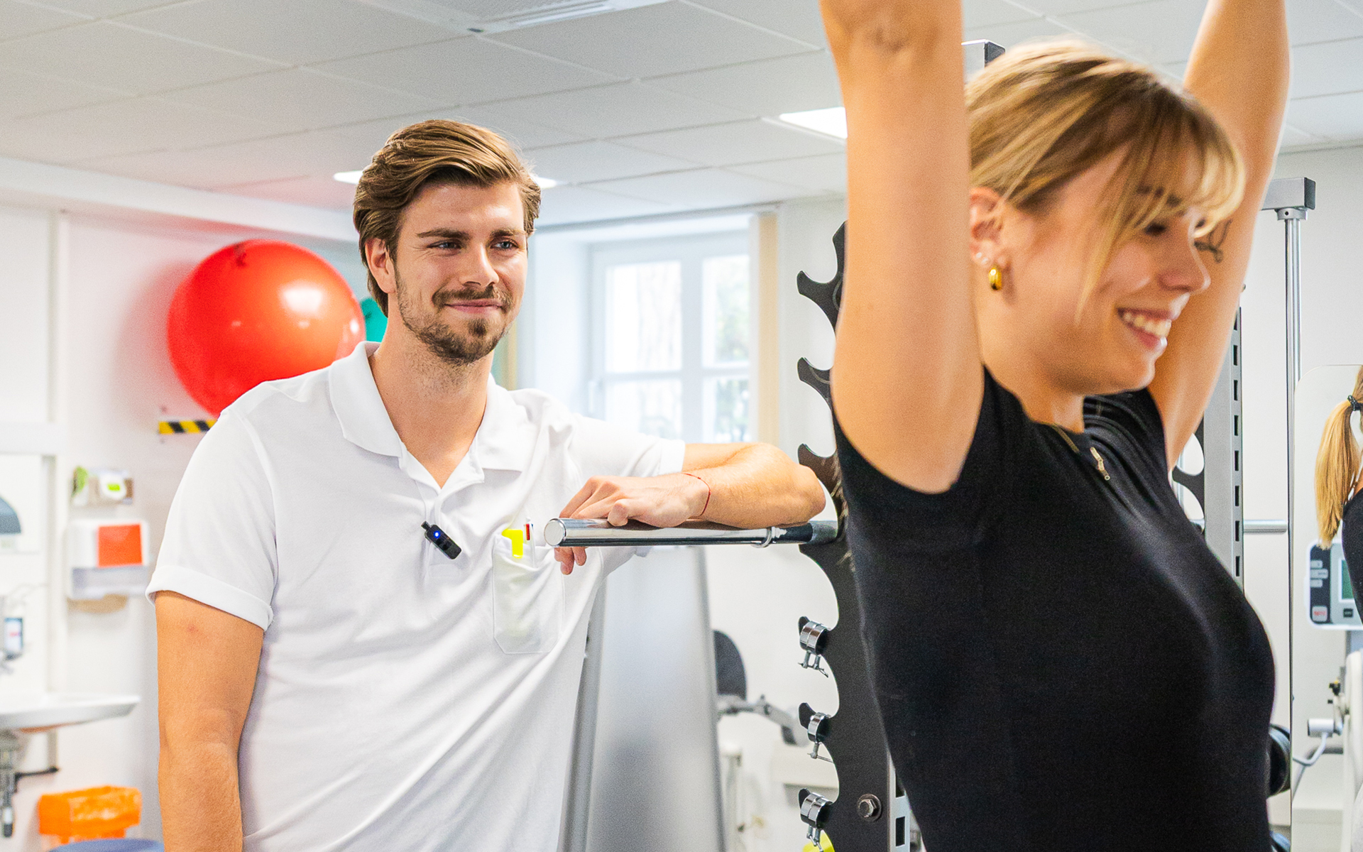 Physiotherapeut begleitet eine Patientin bei einer Übung in der Physiotherapie.