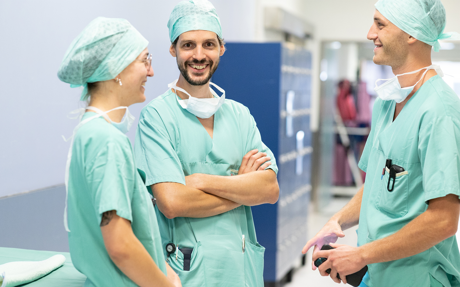 Vier lächelnde medizinische Fachkräfte in weißer Kleidung betrachten gemeinsam Dokumente in einem Ordner.