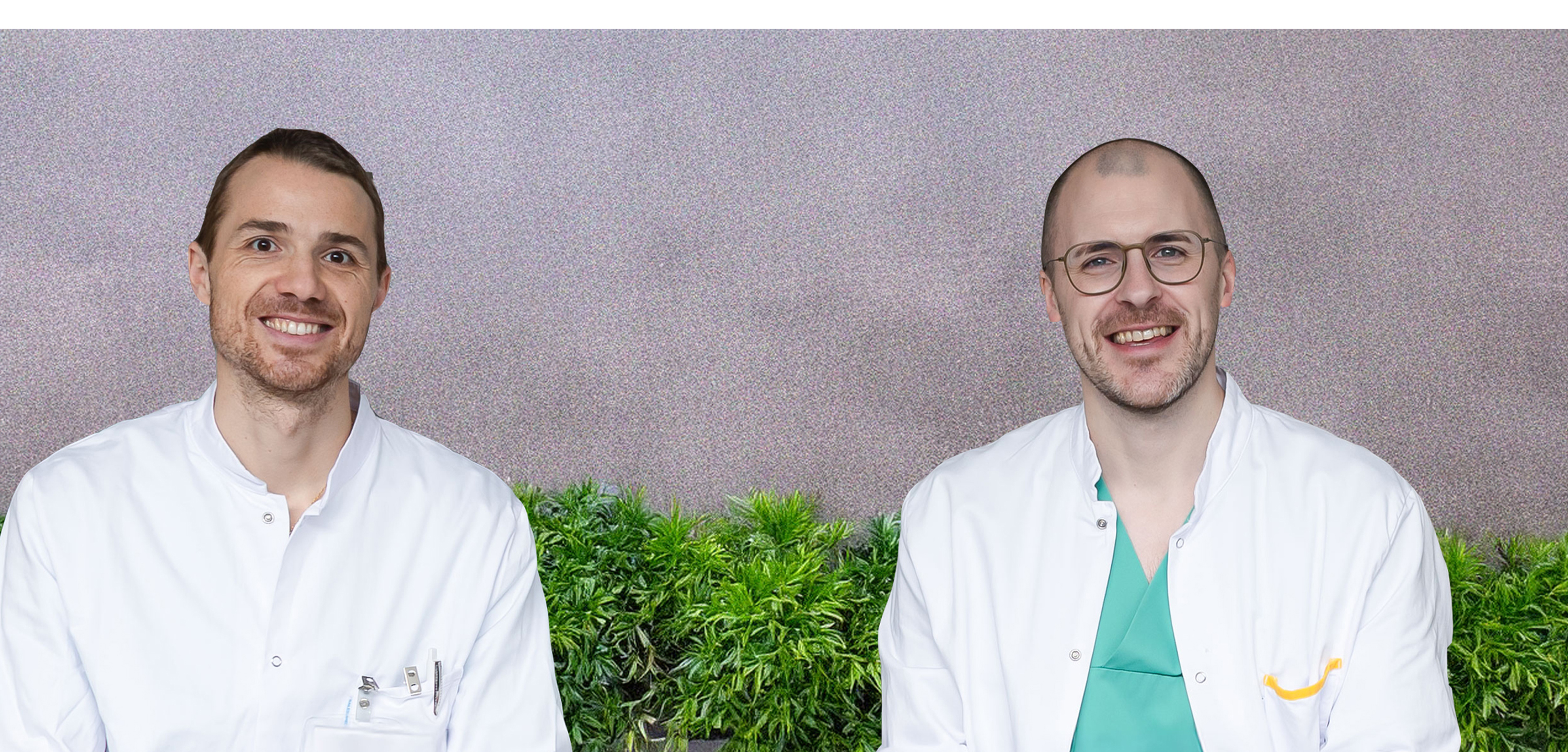 Dr. Mindler und Dr. Kraler sitzen vor einer Häuserwand mit Pflanzen