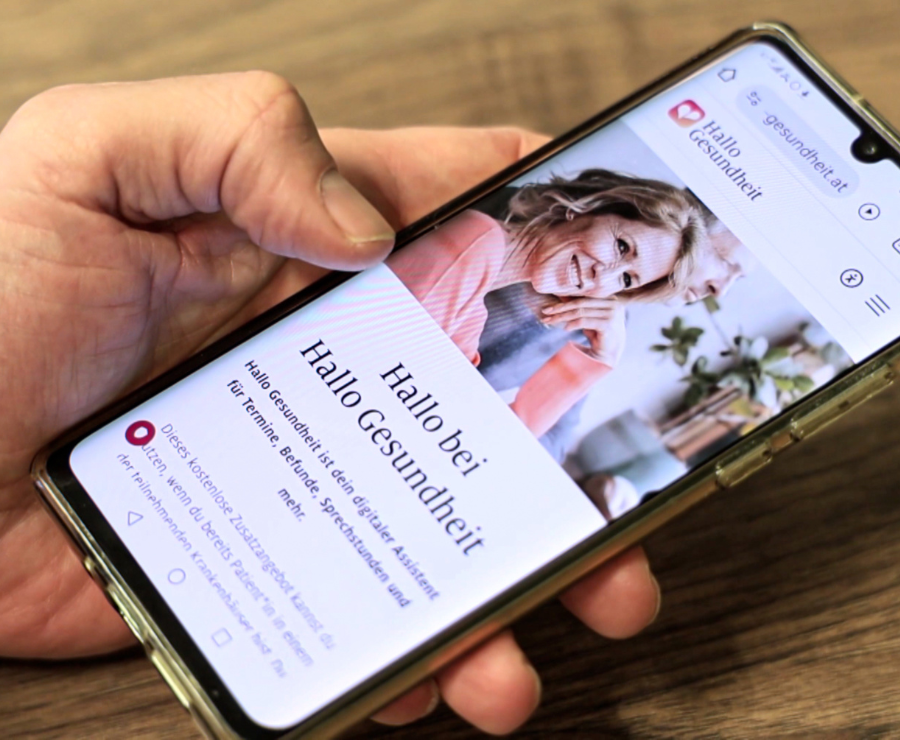 Eine ältere Frau und ein junger Mann lächeln während eines Krankenhausbesuchs.