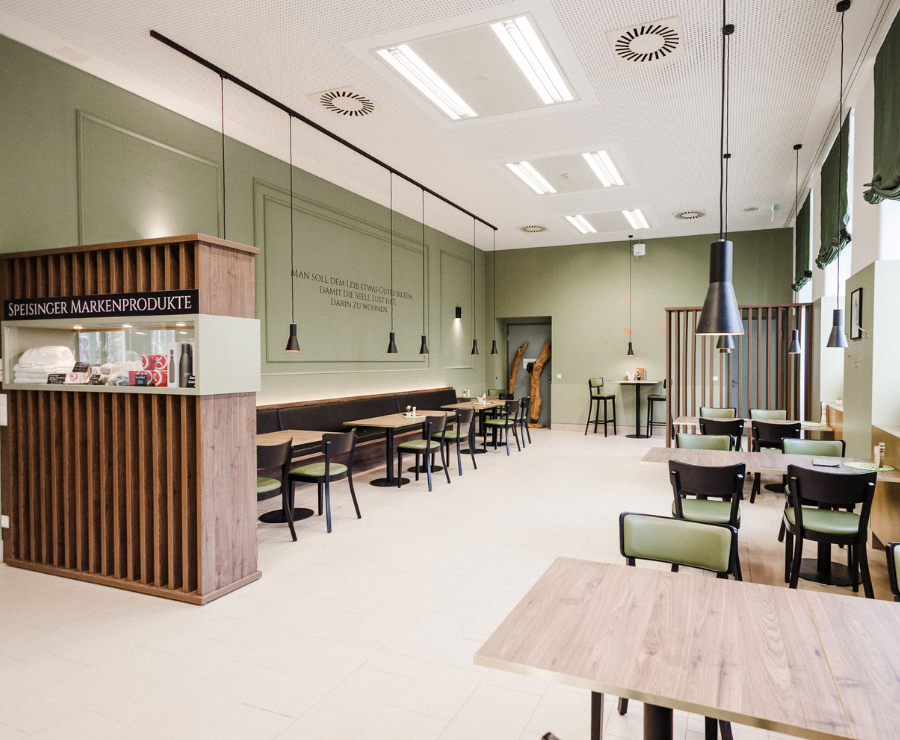 Moderne, helle Cafeteria im Spital Café Kulinario mit grünen Wänden, Holztischen und gemütlichen Sitzplätzen.