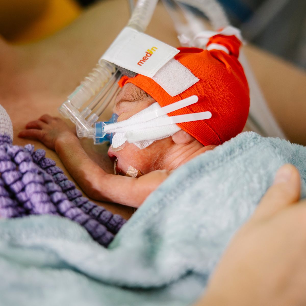 Ein Frühgeborenes, das Atemunterstützung braucht, kuschelt mit seinem Vater auf der Neonatologie.