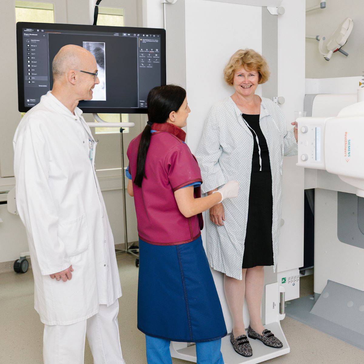 Ein Arzt und eine Radiotechnologin führen eine digitale Durchleuchtung bei einer Patientin durch.