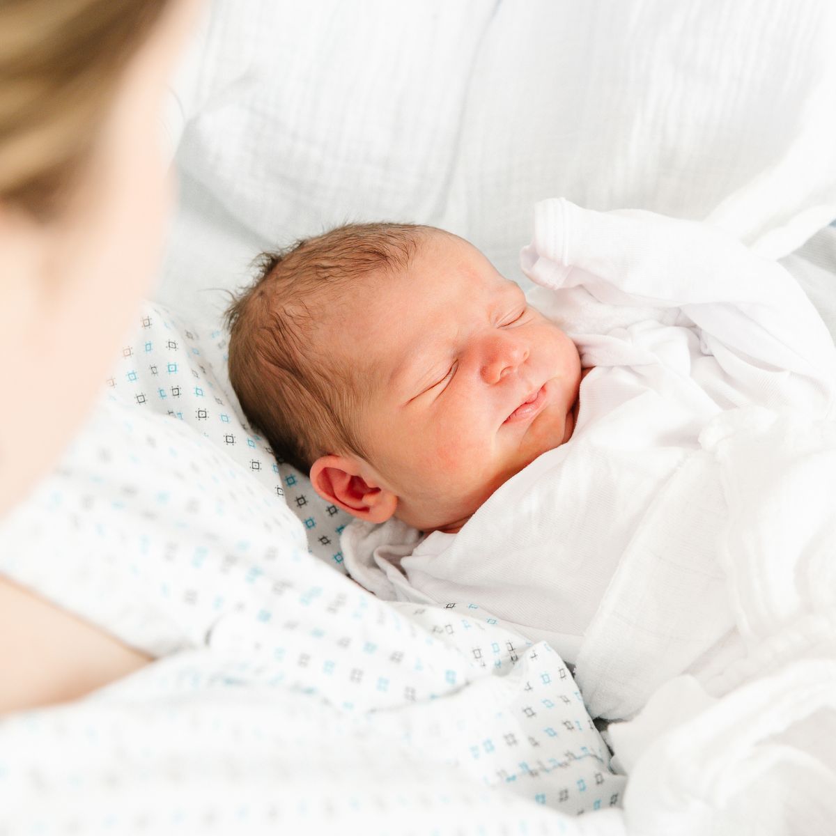 Ein Baby liegt schlafend im Arm seiner Mutter.