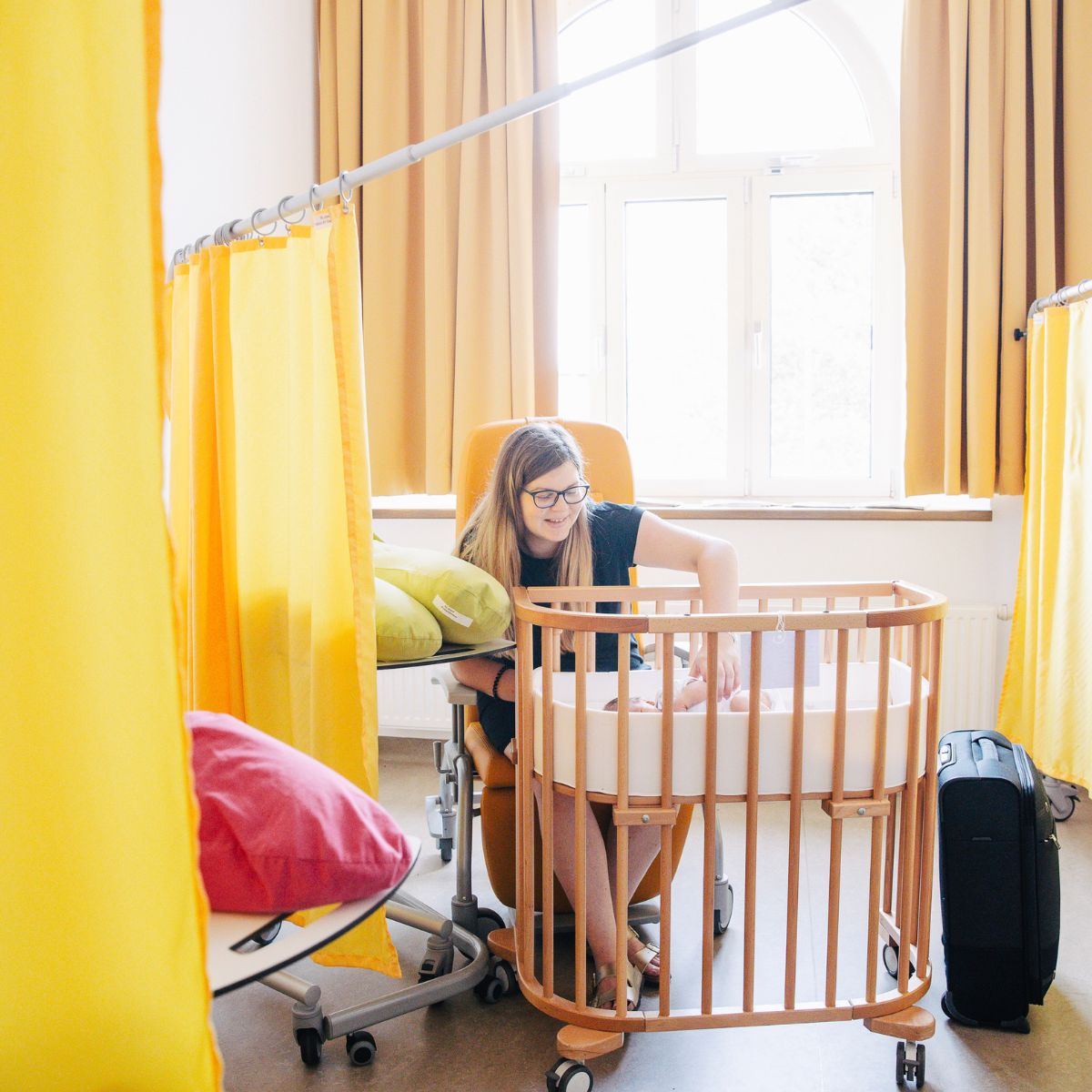 Eine Frau befindet sich mit ihrem Baby, das in einem Babybay liegt, in der Entlassungslounge.