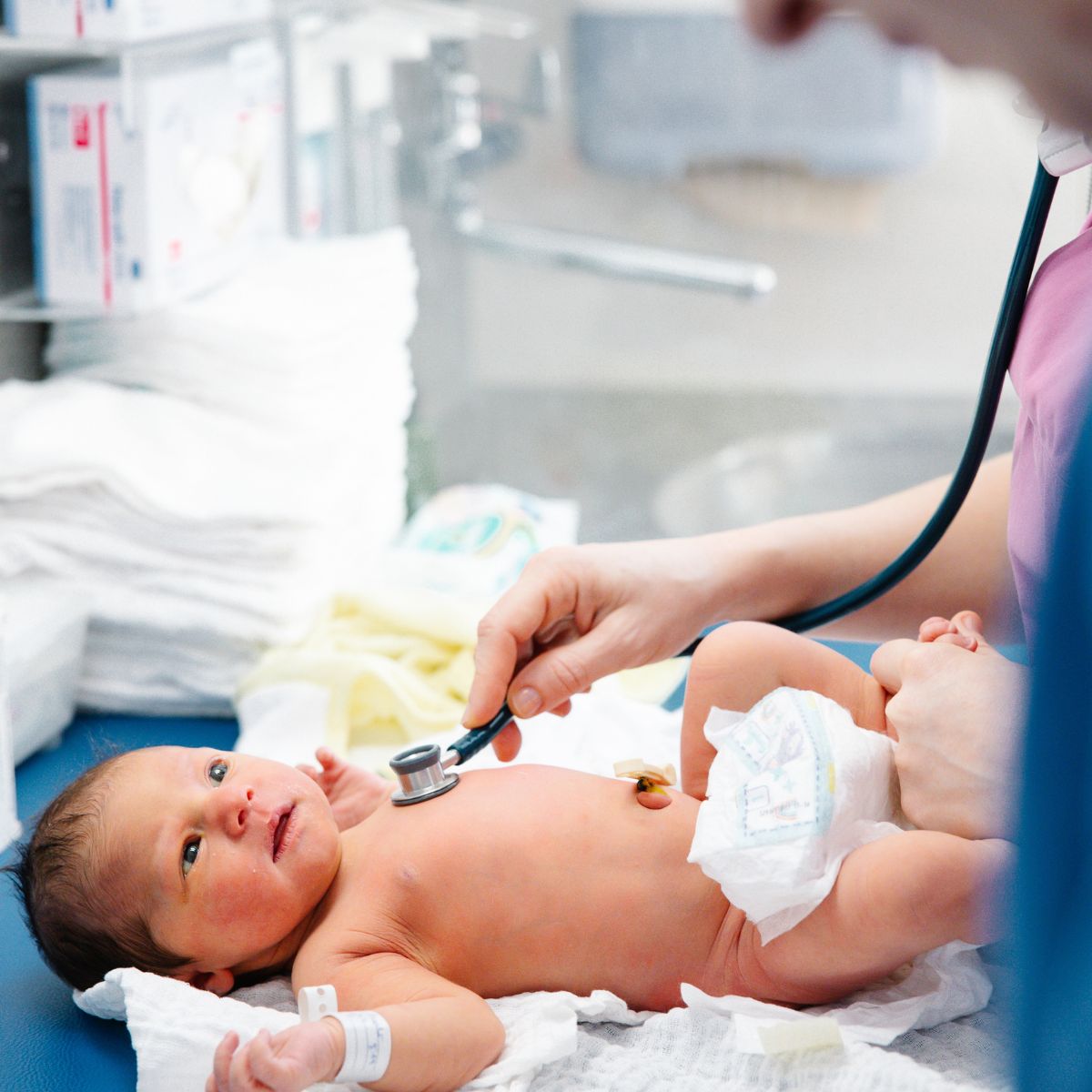 Ein Baby in Windeln wird von einem Arzt mit einem Stethoskop untersucht.