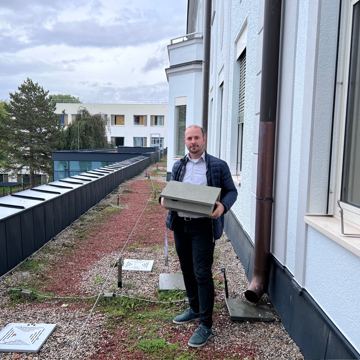 Ein Mitarbeiter des Spitals hält einen speziellen Nistkasten für Mauersegler in der Hand.