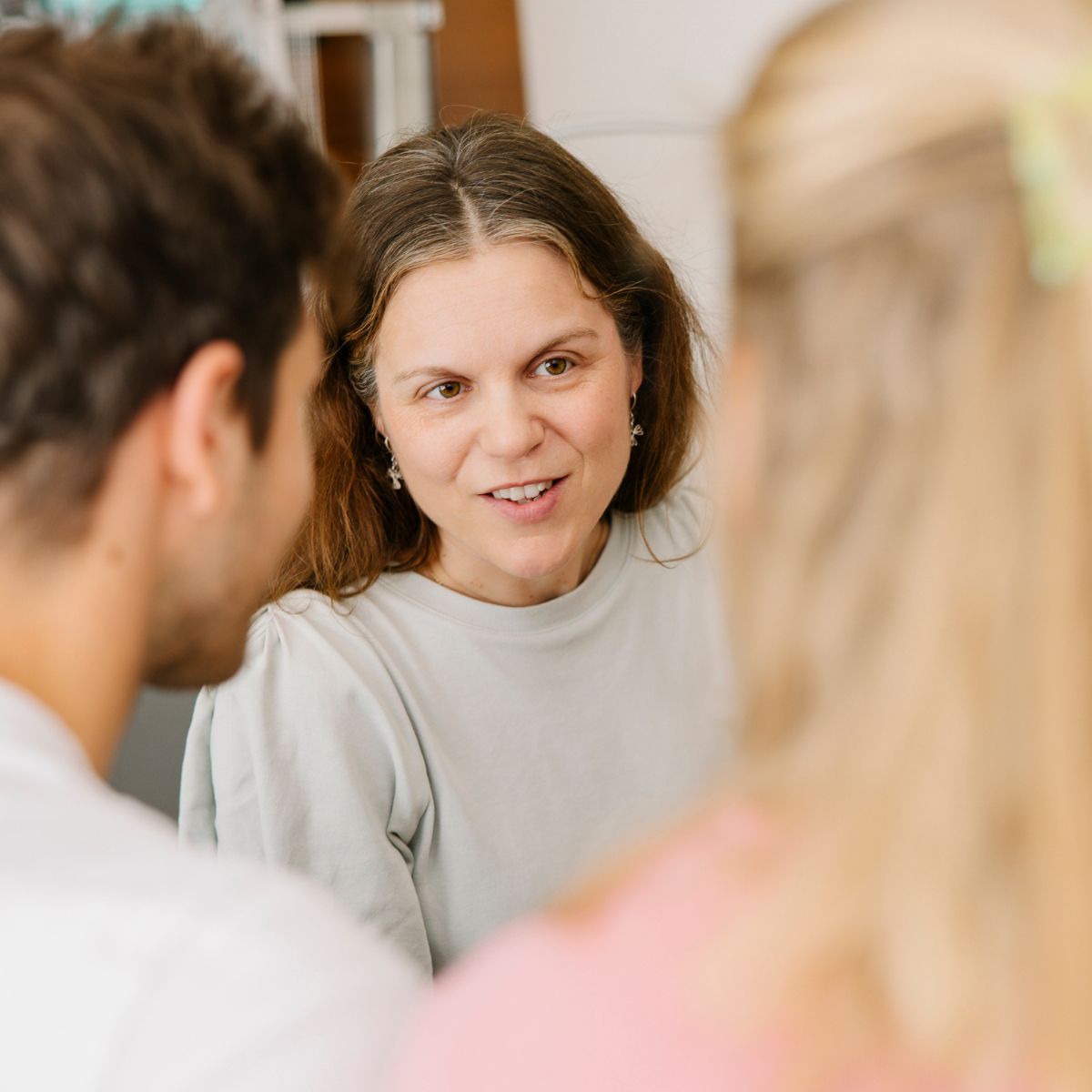 Eine Mitarbeiterin der klinischen Seelsorge im Gespräch mit einem Vater und einer Mutter.