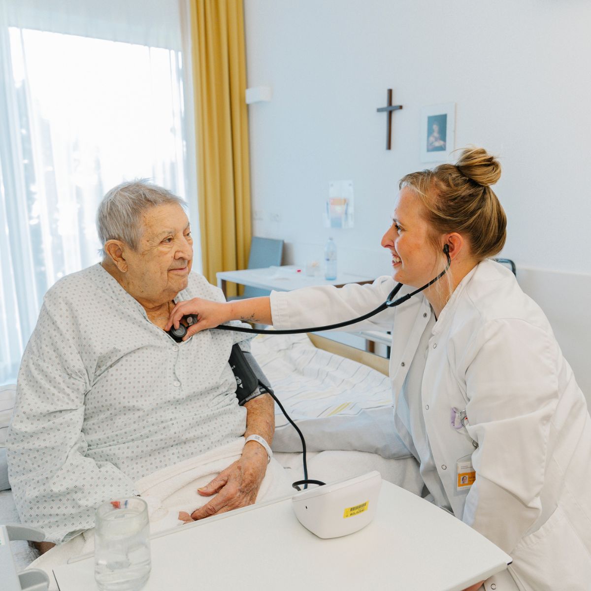 Eine Ärztin hört eine ältere Patientin mit dem Stethoskop ab.