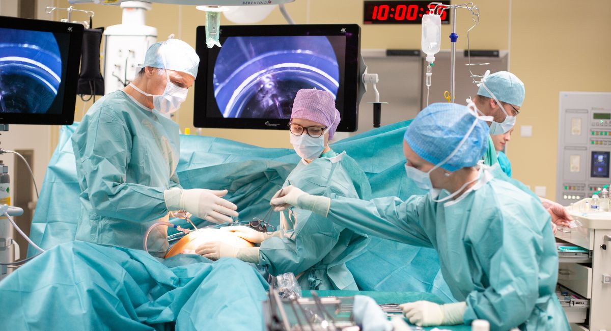 Zwei Chirurgen bei einer Bauchoperation. Ein Chirurg bekommt ein Instrument gereicht.