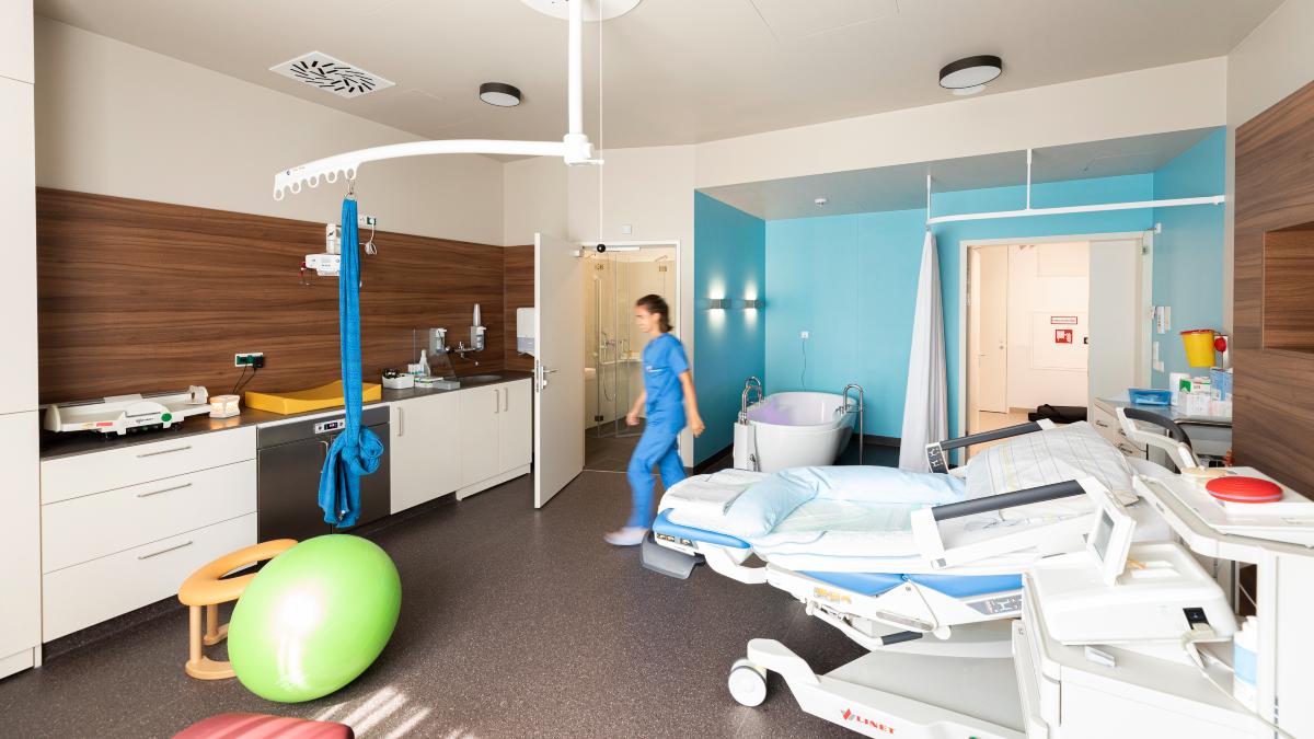 Innenaufnahme eines Kreißzimmers mit Bett, Wanne und grünem Sitzball.
