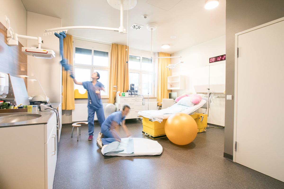 Zwei Hebammen die ein Kreißzimmer für eine Geburt vorbereiten.