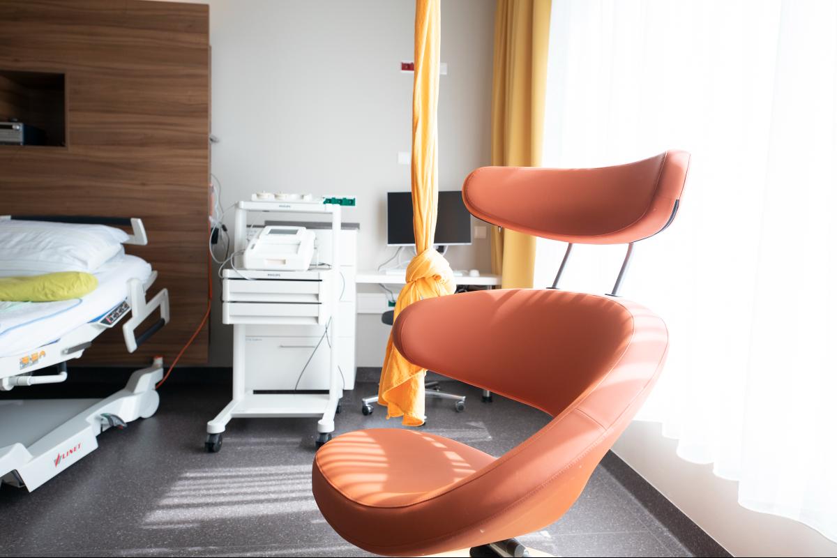Innenaufnahme von einem Kreißzimmer mit einem roten gepolsterten Sessel