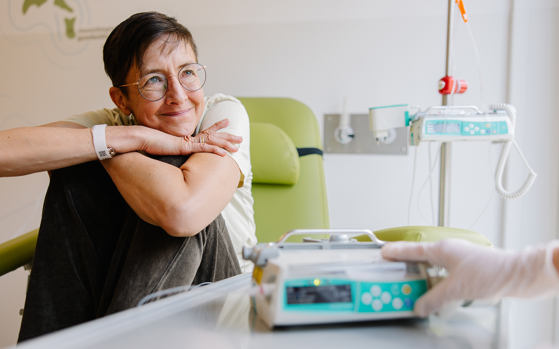 Eine Krebspatientin bei der Chemotherapie lächelt die Pflegerin an.