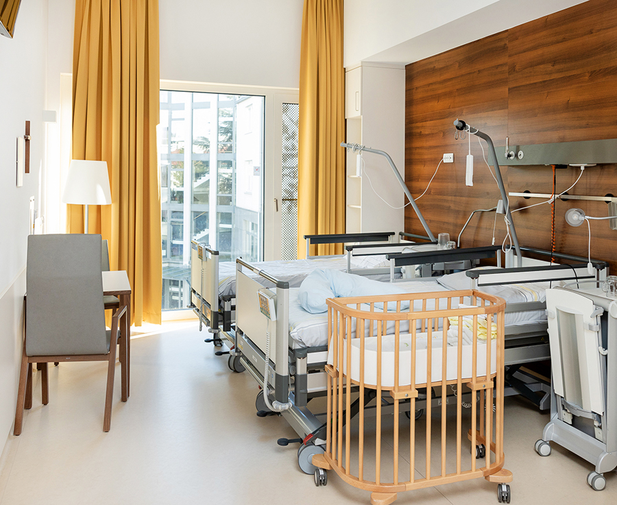 Ein Sonderklassezimmer mit Sitzgelegenheiten, zwei Betten und einem Babybay.