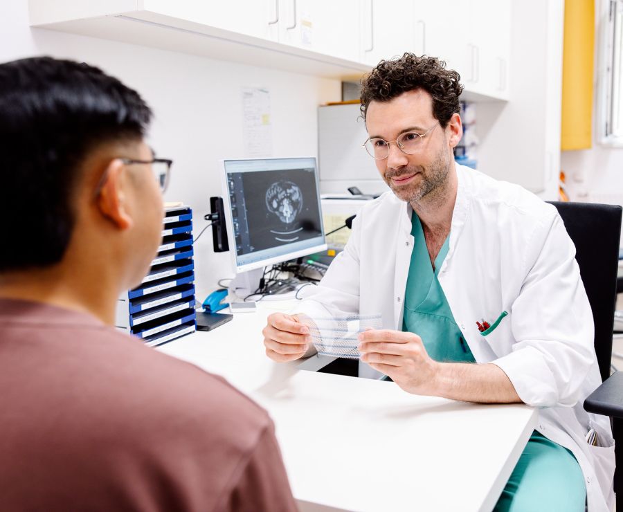 Ein Chirurg führt ein Gespräch mit einem Patienten und hält ein Hernein-Netz..