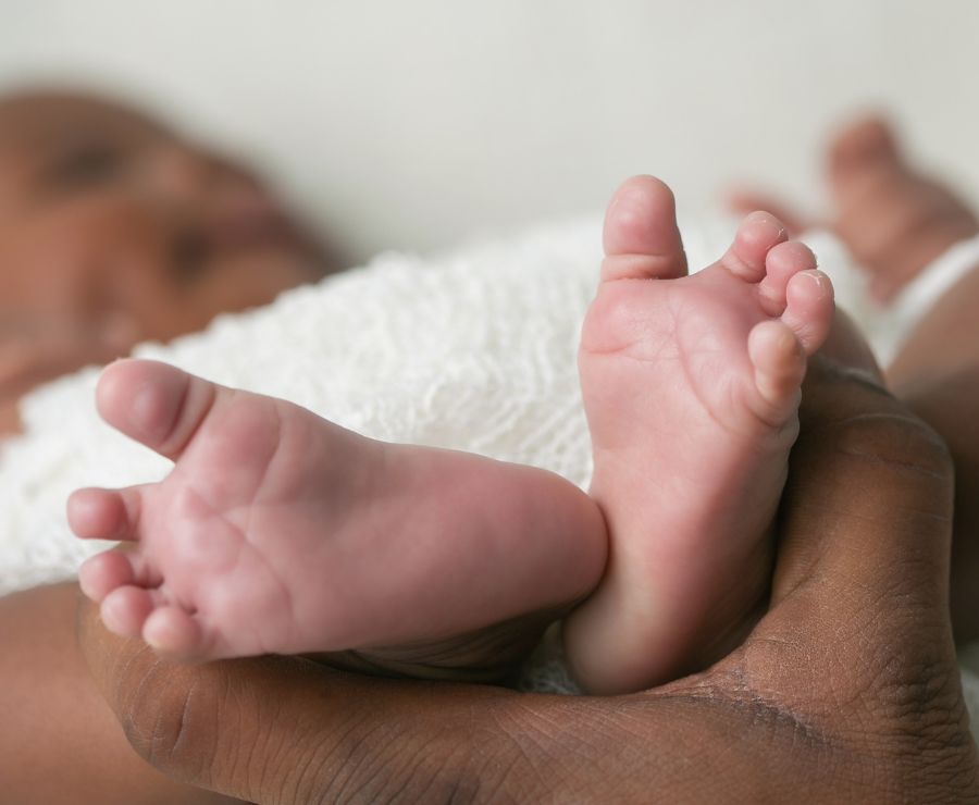 Ein Baby, dessen Füßchen von einer Hand gehalten werden.