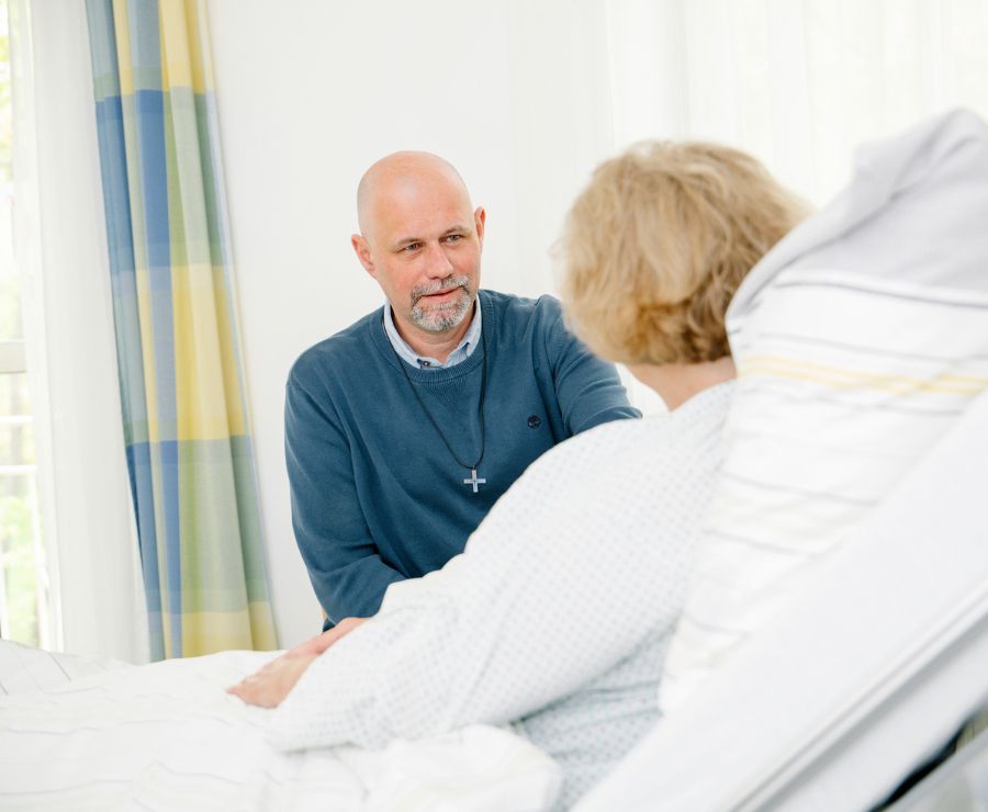 Ein Mitarbeiter der klinischen Seelsorge führt ein Gespräch mit einer Patientin.