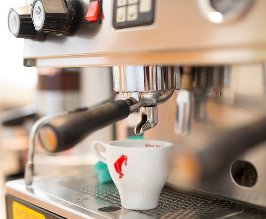 Eine Kaffeetasse, die unter einer Kaffeemaschine steht.
