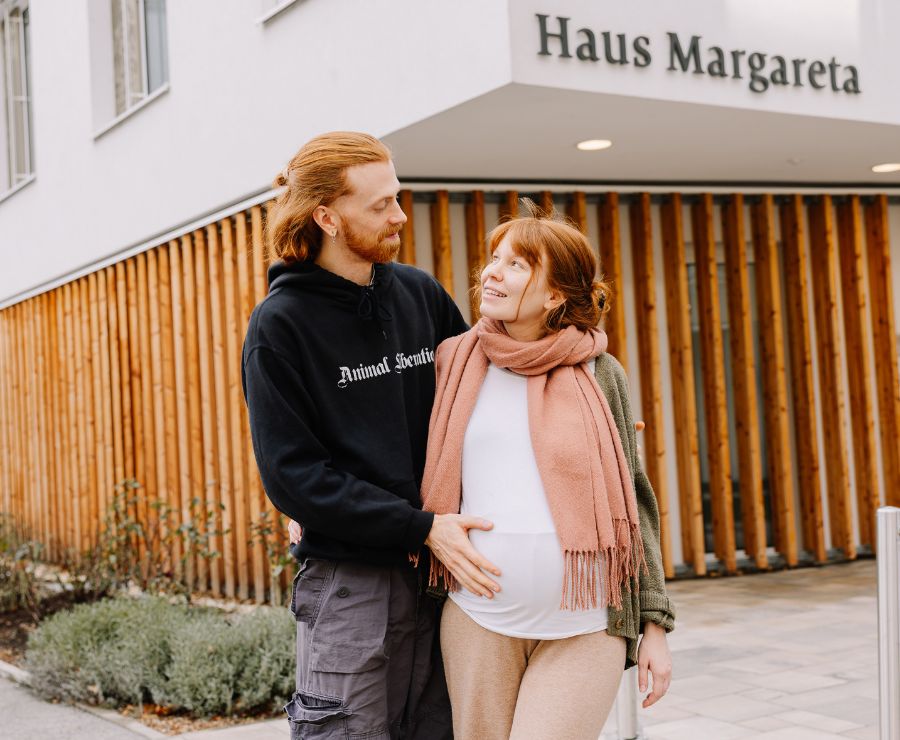 Ein Mann und eine schwangere Frau stehen vor dem Geburtshaus Margareta und schauen sich an.
