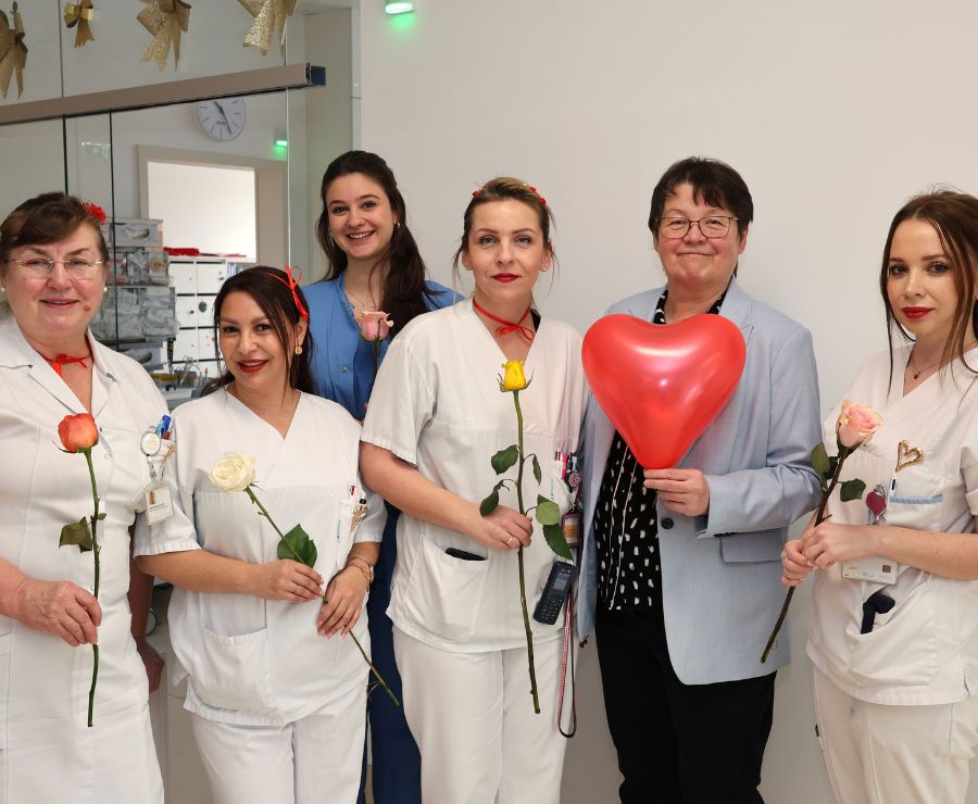 Eine Gruppe von Mitarbeiterinnen steht zusammen, jede von ihnen hält eine Rose in der Hand.
