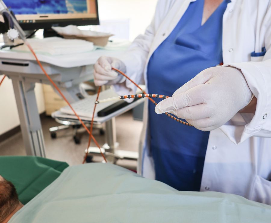 Eine Pflegekraft hält einen Schlauch für eine Untersuchung an einem Patienten in der Hand.