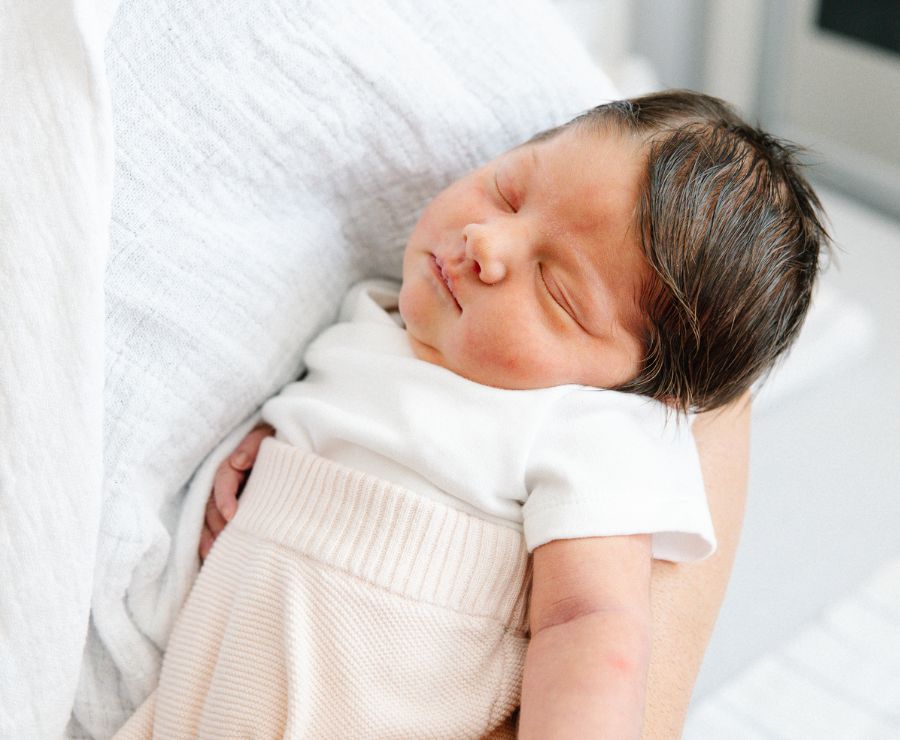 Ein schlafendes Baby in den Armen der Mutter.