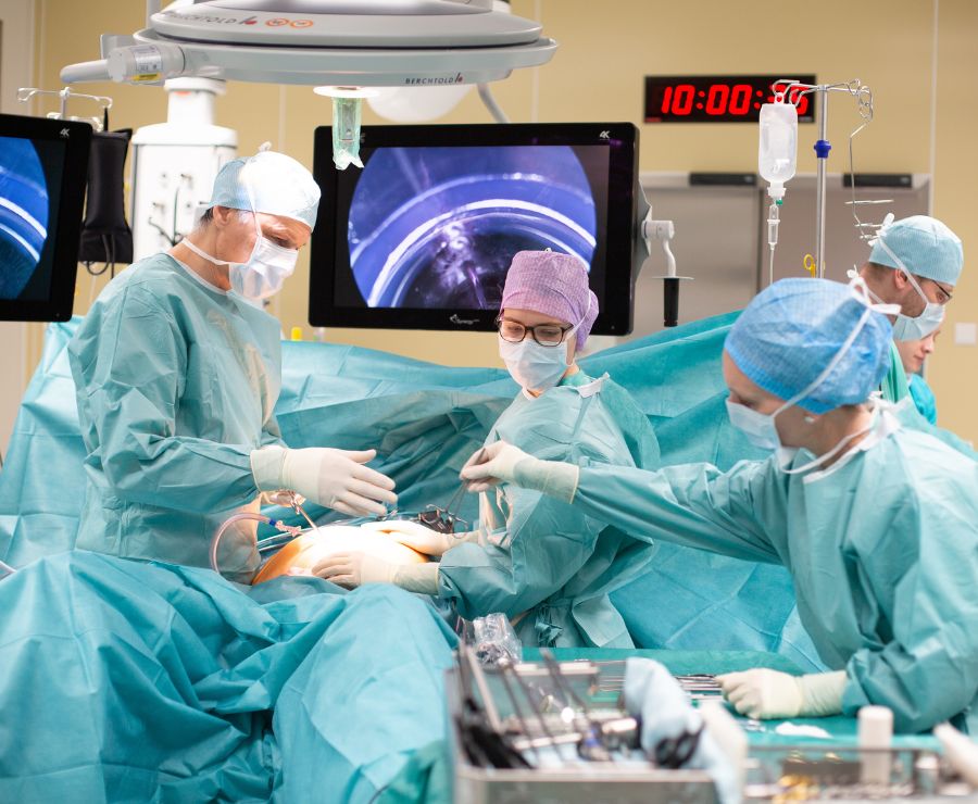 Zwei Chirurgen bei einer Bauchoperation. Ein Chirurg bekommt ein Instrument gereicht.