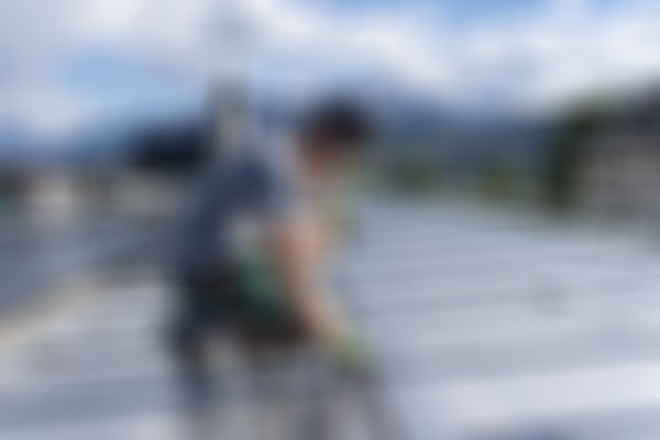 Maschinenringmitarbeiter installiert PV vor Bergkulisse