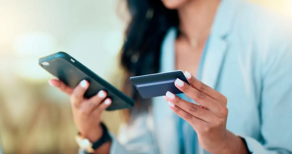 Eine Frau hält ein Handy und eine Kreditkarte in der Hand.